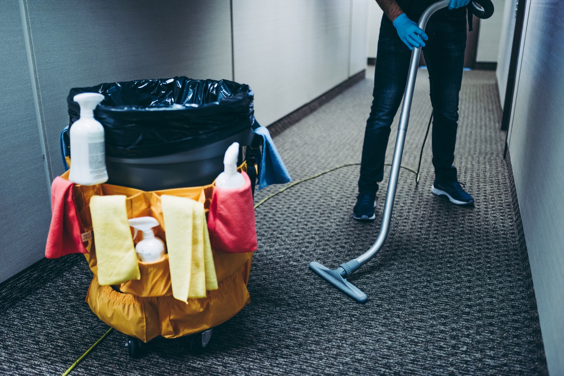 Janitor vacuum cleaning the corridor of an office building.