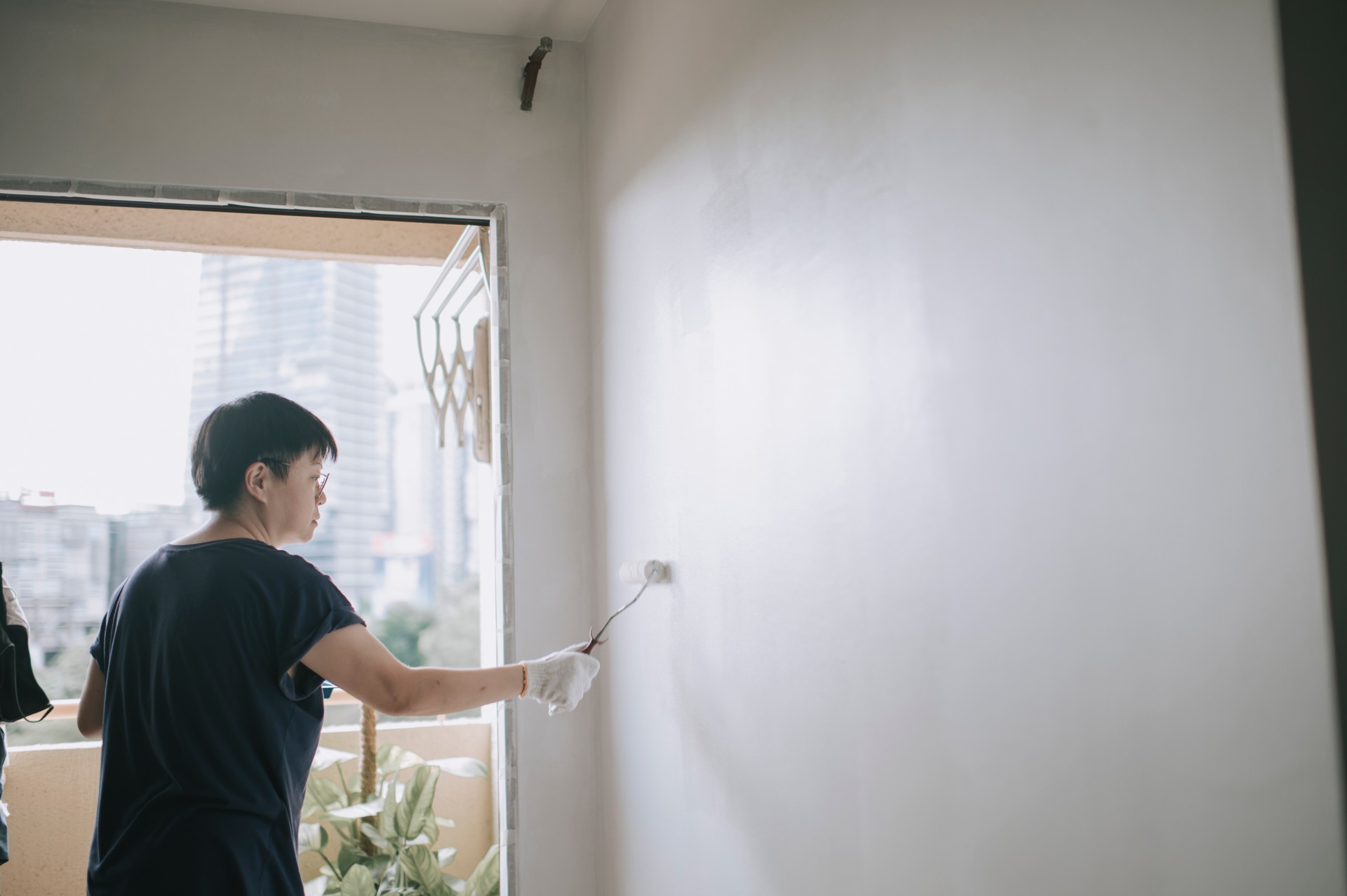 an asian chinese mid adult female painting her living room, apartment renovation